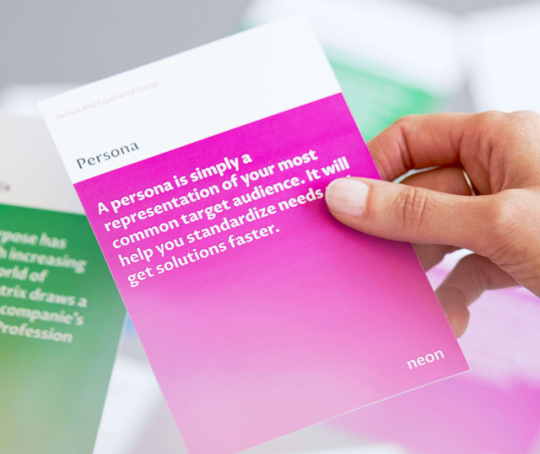 a female hand is holding one of "neons method cards", that explains how to do Personas